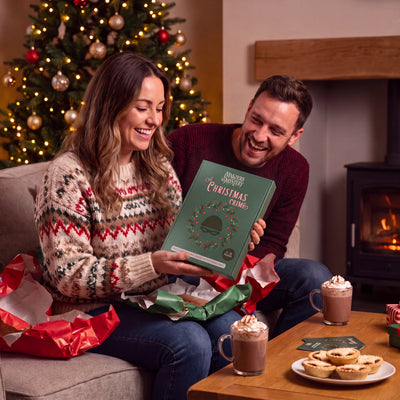Santa’s Workshop Murder Mystery Game boxed game being given as a gift – 1x1 lifestyle image